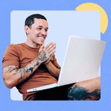 Young man with tattoos using a laptop and smiling