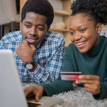 Young black couple using credit card and laptop