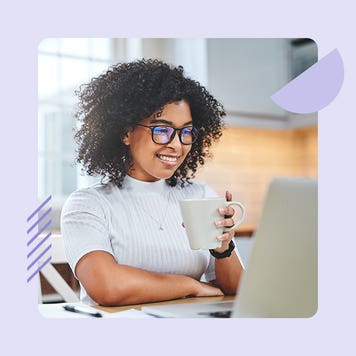 A black woman looks at her laptop.