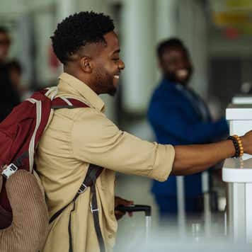 Black man handing passport at airport check in counter.