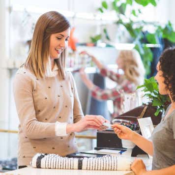 Woman checks out at store counter by paying with her credit card.