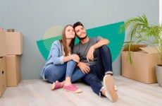 Couple sitting together with boxes stacked around them