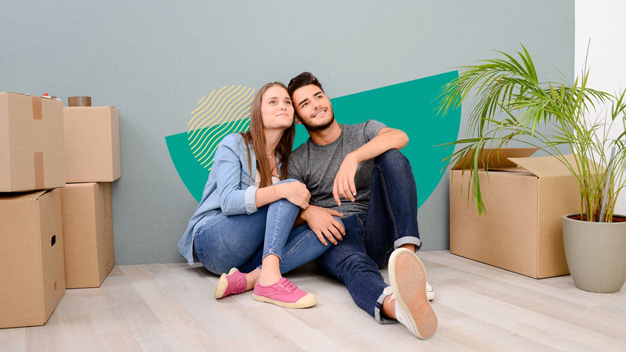 Couple sitting together with boxes stacked around them