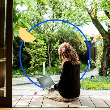 A woman sitting on a porch looking at a laptop