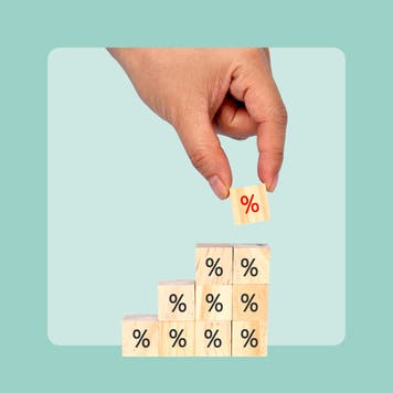 close up, hand stacking blocks with a percent sign carved in them