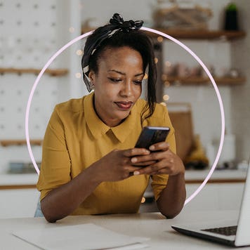 Woman sitting at desk while looking at cell phone