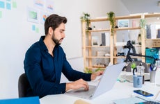 Entrepreneur looking at document while using laptop in office