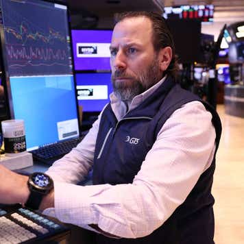 A trader on the floor of the New York Stock Exchange looking at at a monitor with a concerned look on their face.