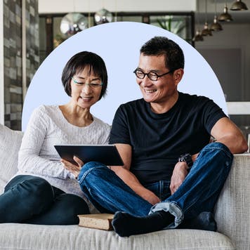 Couple sitting on couch looking at tablet