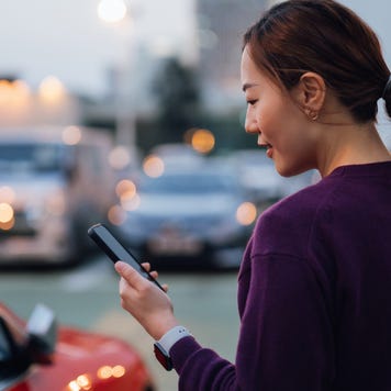 Person on smartphone standing near car