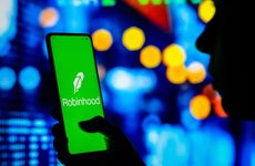 Woman holds a smartphone with the Robinhood Markets logo displayed