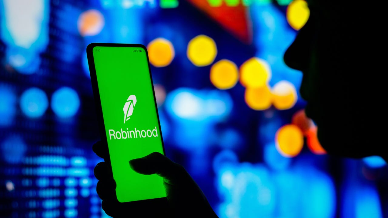 Woman holds a smartphone with the Robinhood Markets logo displayed