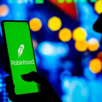 Woman holds a smartphone with the Robinhood Markets logo displayed