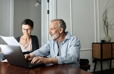 Couple discussing business paper sitting in front of laptop