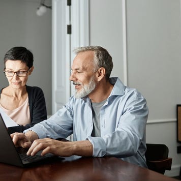 Couple discussing business paper sitting in front of laptop