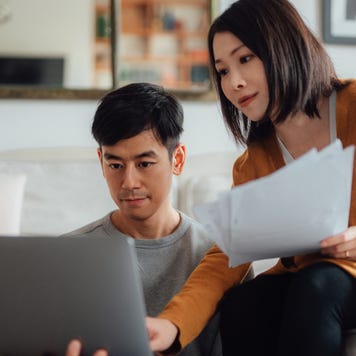 Young couple discussing over financial bills while using laptop on sofa