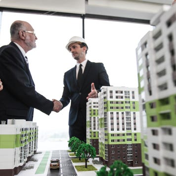 Business people standing near houses models