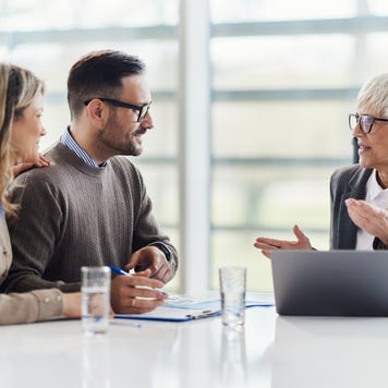 Senior agent talking to a couple in a meeting in an office.