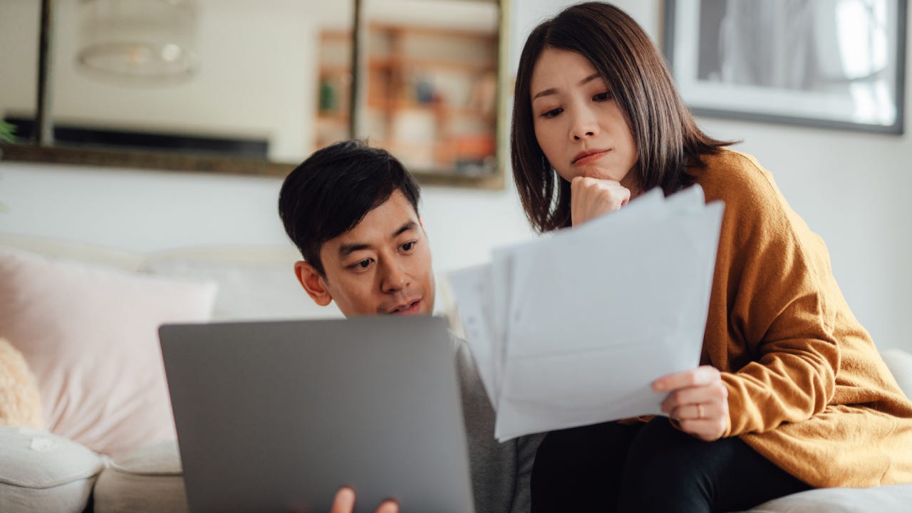 Young couple discussing over financial bills while using laptop on sofa