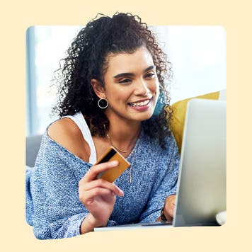 design image of a woman holding a credit card in her hand and smiling at her laptop screen