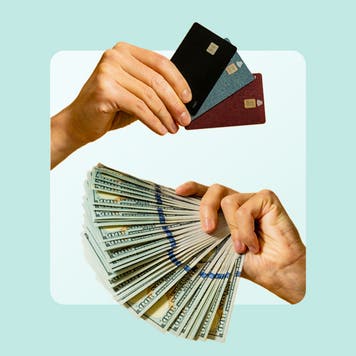 photo of credit cards over a handful of cash both fanned out and held by two different hands