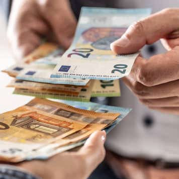 Businessman's hands exchanging euro banknotes, closeup shot.