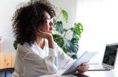 young woman working at home office using multiple devices