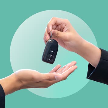 A close-up of two hands exchanging a car key fob. Image is on a green background.