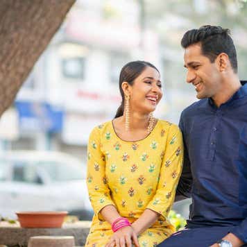 An Indian couple sits side by side while looking at each other lovingly.