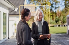 Realtor showing information to client outside suburban house