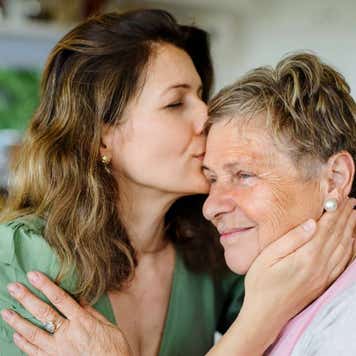 A young woman kisses her grandmother on the cheek.