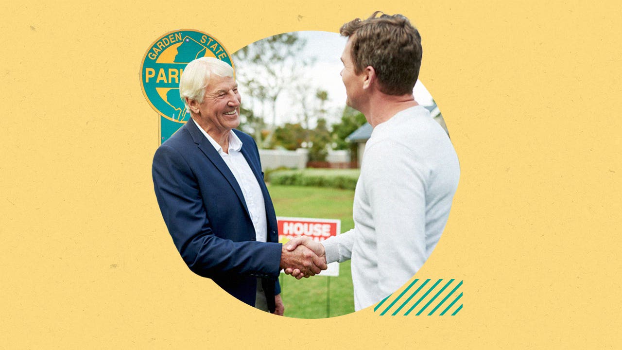 Two men shaking hands in front of a house for sale sign