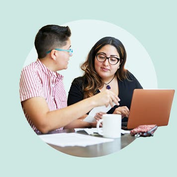 A couple reviewing a note and looking at a laptop.