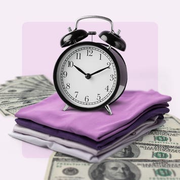 Analog alarm clock on top of a pile of cash