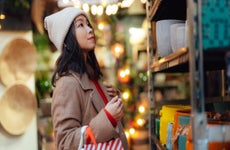 woman with shopping bags choosing gifts at Christmas market