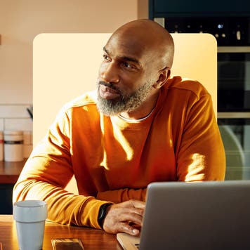 A man works on his laptop in his kitchen.