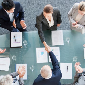 Business people shaking hands across conference room table