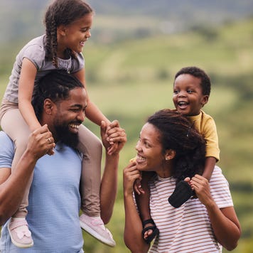parents carrying their small kids on shoulders in nature