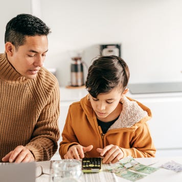 Dad and son with cash sitting in the kitchen
