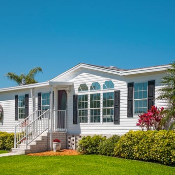 Luxury caravan, mobile home, landscaped with front lawn, palm trees, clear sky