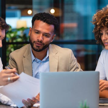 People talking to a person in front of a laptop