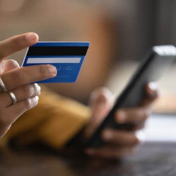 Close up cropped view of someone shopping on mobile phone with a credit card