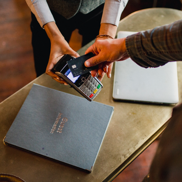 A directly-above shot of a man paying with his credit card on a credit card reader.