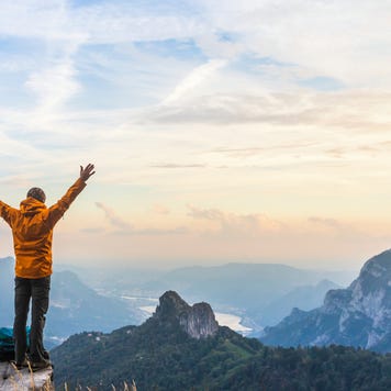 Happy hiker with raised arms on top of the mountain