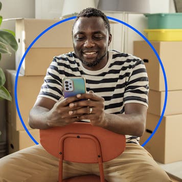 Person sitting in chair looking at phone and smiling
