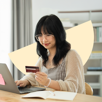 Woman at table holding credit card and typing on laptop