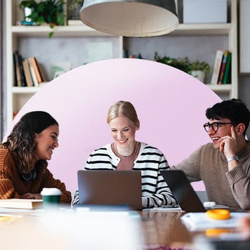 Three colleagues sitting and working together around a laptop.