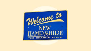A blue sign with gold lettering saying "Welcome to New Hampshire The Granite State"