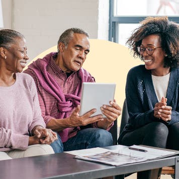 3 people sitting together, looking at a tablet