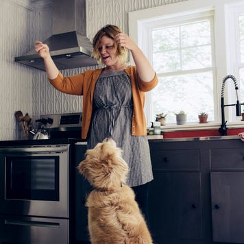 Woman feeding treats to dogs in kitchen